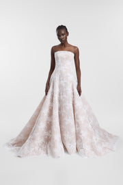 A model wearing an ivory strapless lace wedding gown with a structured bodice, full skirt and long train, photographed against a seamless light grey studio background.