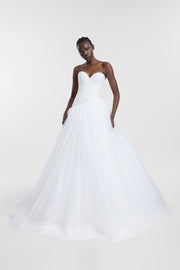 A model wearing an ivory strapless tulle wedding gown with a sweetheart neckline, draped waist and full layered ballgown skirt, photographed against a seamless light grey studio background.
