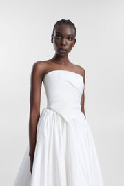 A model wearing an ivory strapless satin corset with a straight neckline, asymmetrical draping and pointed hem, photographed against a seamless light grey studio background.