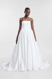 Model wearing the Cleo ivory strapless ballgown with a straight neckline, full gathered skirt and sweeping train.