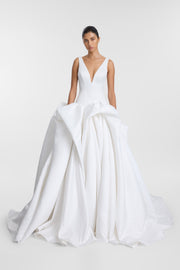 Model wearing the Bailey ivory duchess satin ballgown with a deep V neckline, fitted bodice, voluminous draped skirt and sweeping train.